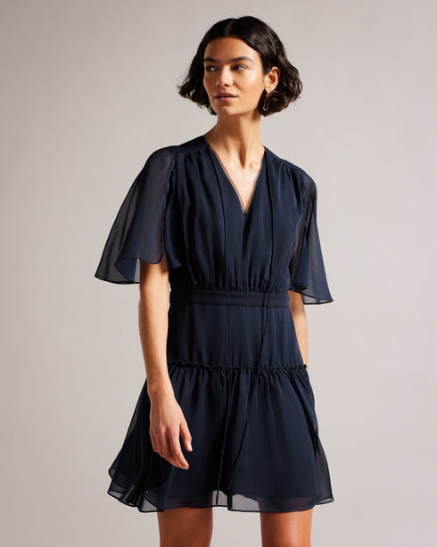 GIGGIE-Dresses-Add a touch of retro style to your wardrobe with GIGGIE. This dress features a fit and flare silhouette, with sheer fluted sleeves and a ruffle tiered skirt that are sure to make you stand out at your next event.The shell of this product is made of 100% recycled polyester. Using recycled polyester helps divert plastic waste from ending in landfills and helps us to reduce our dependency on virgin materials. Mini dress Tiered skirt with ruffles Fit and flare Sheer fluted sleeves Neck tie V neck
